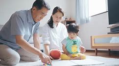 A senior couple drawing with their 2-year-old grandson