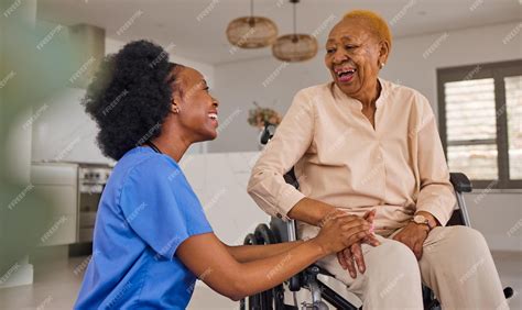 Black people nurse and senior holding hands in wheelchair elderly care and healthcare at home ...