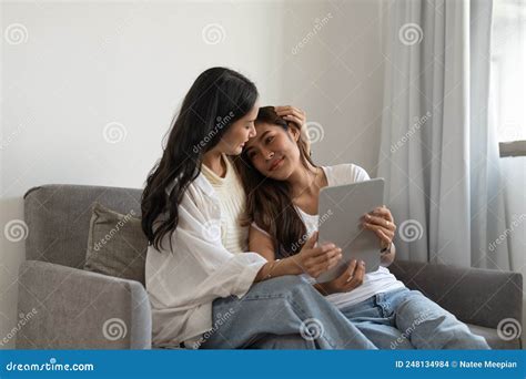 Happy Lesbian Couple Hugging Having Fun Using Digital Tablet Relaxing on Couch at Home. Two ...