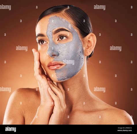 Woman, face skincare and mud mask on orange background in studio self ...