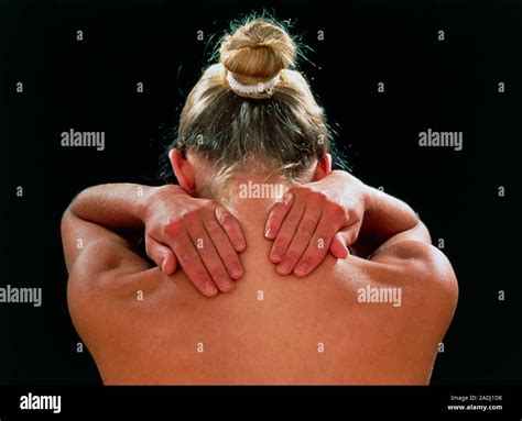 Neck and shoulder pain. Posterior view of the head and upper back of a young woman, her hands ...