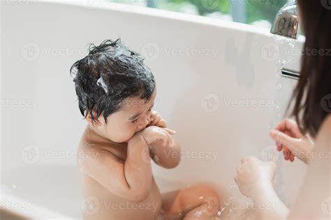 Asian cute kid girl toddler having a bath wash hair cleaning bathing bath tub with her mother ...