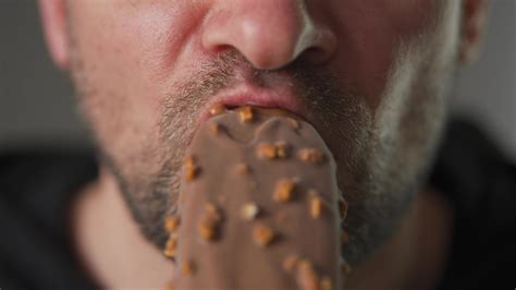 Man enjoying eating chocolate covered ice cream with nuts 24843193 ...