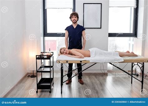 Caucasian Male Massage Therapist Stands Next To Client Lying on Massage ...