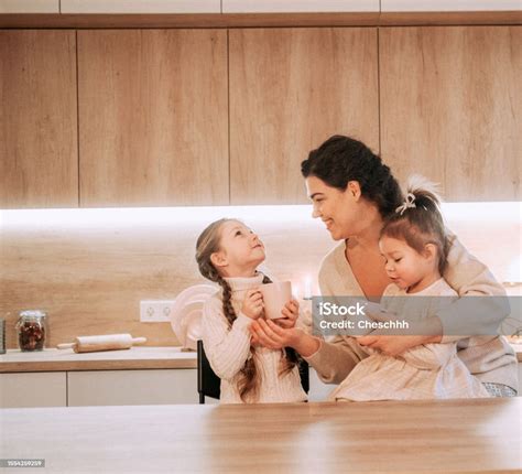 Two Little Sister Girls Are Drinking Tea With Their Mother In The ...