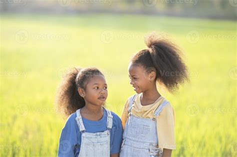 Outdoor close-up shot of two cute black sisters smiling at sunset ...