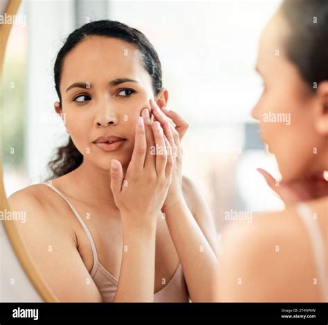 Cant have any pimples. a young woman popping a pimple on her face in ...