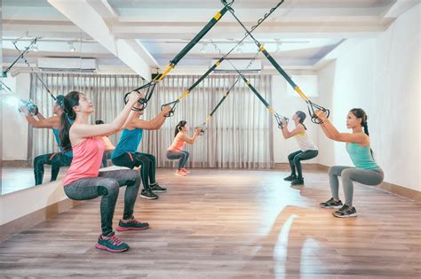 Premium Photo | Group of young asian people doing squat with fitness suspension straps. healthy ...