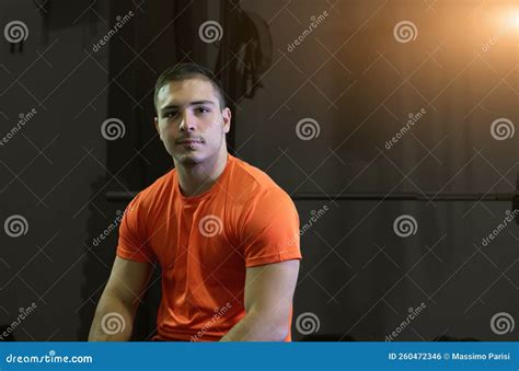 Athletic Young Man Poses Seated on the Bench Press Looking at the ...