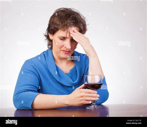 40 something woman staring at a glass of wine looking very upset Stock Photo - Alamy