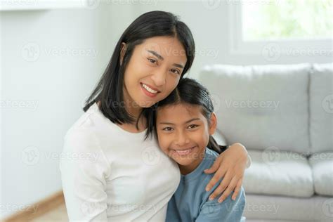 single mom happy together with daughter. Asian young mother smile and hug daughter in home. love ...
