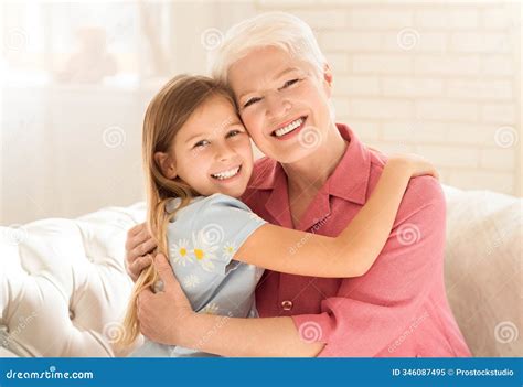Happy Granny With Granddaughter Hugging On Sofa At Home Stock Image ...