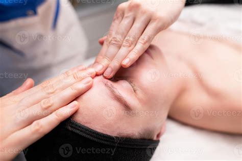 Facial massage beauty treatment. Close-up of a young woman face lying ...
