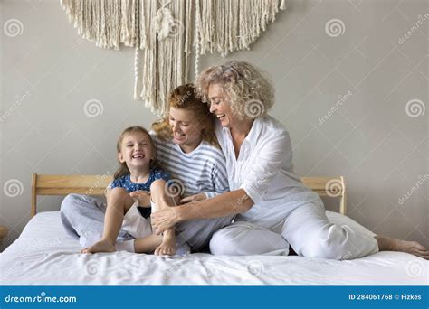 Joyful Granny and Mom Tickling Cuddling Little Child on Bed Stock Photo ...
