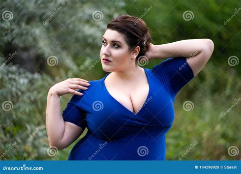 Plus Size Fashion Model in Blue Dress with a Deep Neckline Outdoors ...
