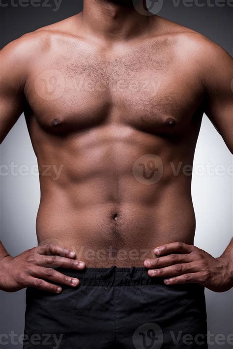Perfect male body. Close-up of shirtless African man holding hands on ...