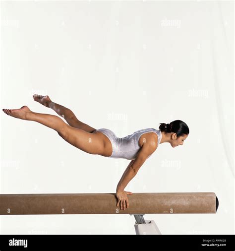 Young female gymnast performing routine on balance beam, side view ...