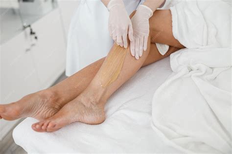 Premium Photo | Woman client having hair removal procedure on leg using sugaring paste in beauty ...
