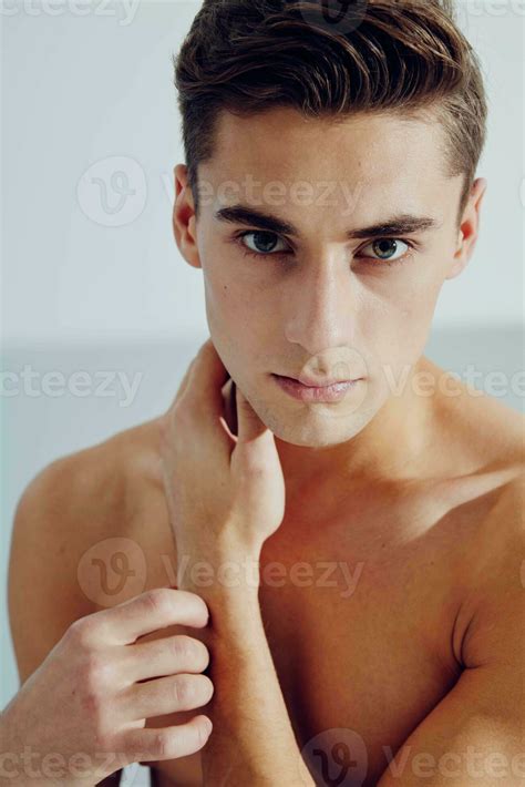 Cute guy touches his neck with his hand portrait of a naked torso ...