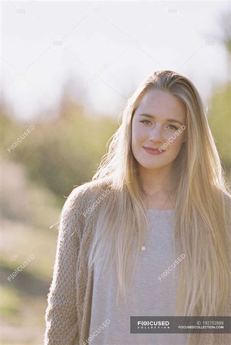 Portrait of young adult woman with long blonde hair in garden ...
