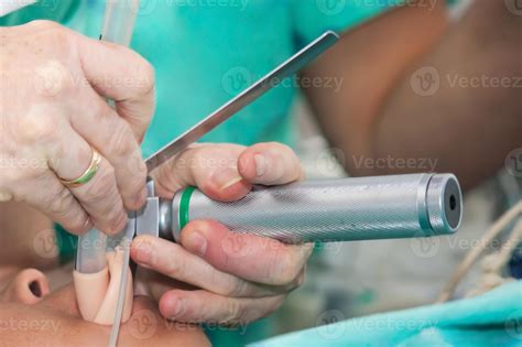 Anesthesiologist performing an endotracheal intubation to a female patient at the beginning of a ...