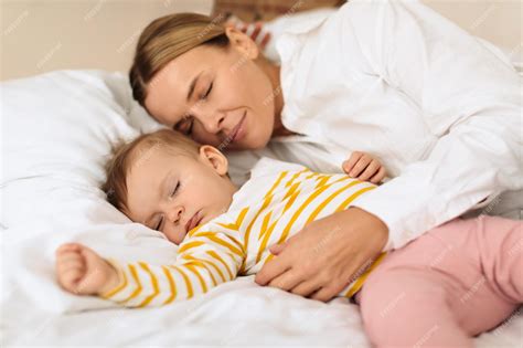 Premium Photo | Peaceful mother and cute little child girl lying on bed sleeping together mom ...