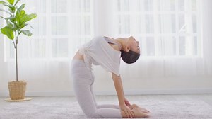 Attractive Asian woman practice yoga Ustrasana pose or yoga Camel pose deep breath to meditation in bedroom after wake up in the morning Feeling so comfortable and relax,Yoga for Healthcare Concept
