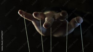 The puppeteer's hand controls the puppets on strings. Manipulation concept