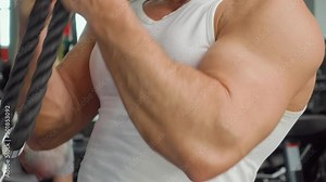 Bodybuilder performs exercise in biceps simulator in the gym. Sports training