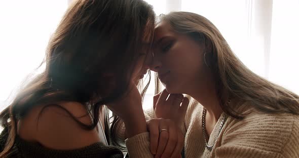 Two Young Women Lesbian in Love Sitting Close and Touching Each Other Tender