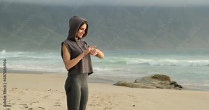Female runner looking at smart watch heart rate monitor. healthy lifestyle using smart watch and application. Technology and sport concept. sports girl resting on the beach after jogging