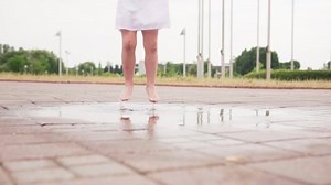 clip-1031638013-child-barefoot-jumps-puddle-on-city-street