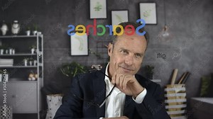 Handsome mature businessman in front of the computer screen at work or at home typing in an anonymous search engine the word GIFT for a festivity. Christmas. View through the pc monitor. Cine lens. Stock ビデオ