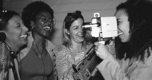 Group of multiracial girls having fun dancing and listening music together while using vintage film camera outdoor - Party, nightlife and people lifestyle concept - Black and white editing