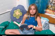 preteen girl bed sitting her book reading long blond haired alamy