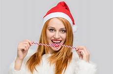 cane candy woman front smiling holding santa hat young beautiful eating stock