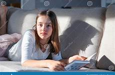 tween cute couch sofa girl lying hard shadow portrait camera looking funny light book