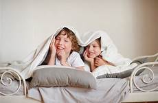 bedroom squirmy brother sister bed children two blanket smile under look little