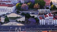 Establishing aerial shot of Lisbon old city on sunset. Drone flying from the Tagus River towards Rocha Conde de Obidos Viewpoint