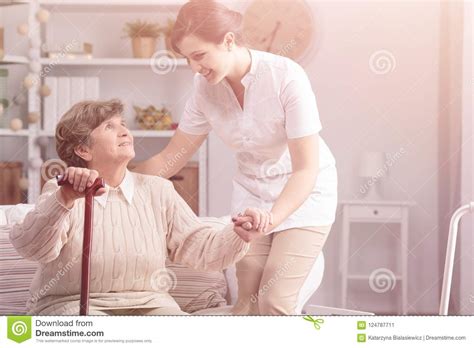 Helpful Caregiver Supporting Smiling Senior Woman With Walking Stick ...