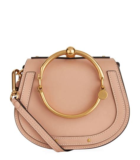 The shoulder bag has a gold loop handle, an optional adjustable leather shoulder strap, a rear patch pocket, and gold hardware. Chloé Natural Small Nile Bracelet Bag | Chloe nile bag ...