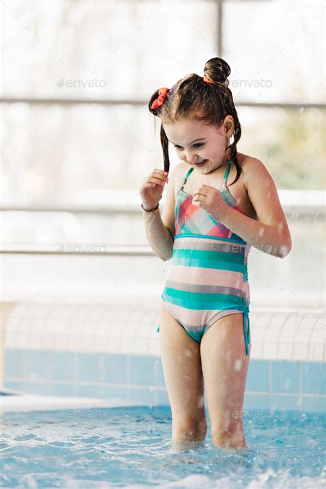 Gorgeous blonde teen playing shower. Little girl with wet hair standing in a kid's pool. Stock ...