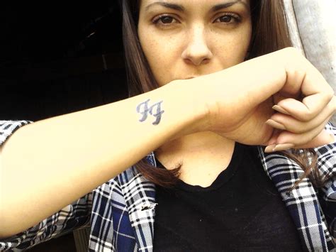 a woman with a small tattoo on her arm posing for the camera while