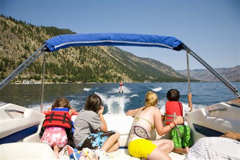 Boat rental & charter sporting goods. Family in a motorboat and looking at a person waterskiing ...