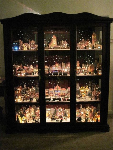 Decorating for christmas is a tradition families look forward to every year. Christmas village displayed in a curio cabinet with led ...