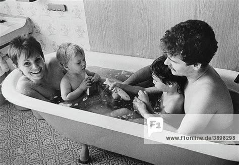 Wohnungen an der nordseite von gebäuden sind meist eher kühl und oft auch wenig lichtdurchflutet. Junge Familie in Badewanne, DDR, Deutschland, Europa, ca. 1986