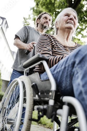Sohn schiebt seine demenzkranke Mutter, Seniorin, im Rollstuhl - Stock ...