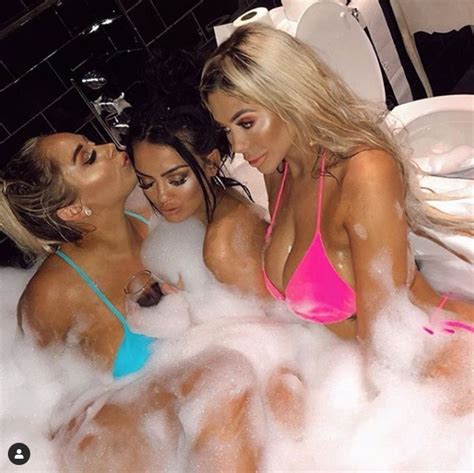 Low section of young woman with illuminated lighting equipment in bathtub. Chloe Ferry poses in tiny pink bikini in soapy bubble bath