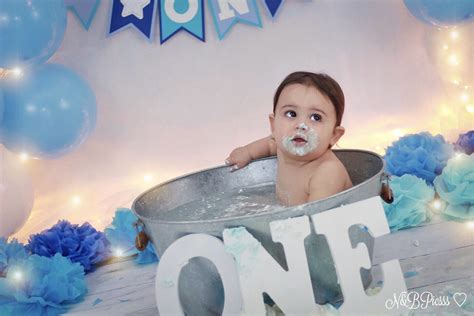 Happy baby face in bubble bath. Baby boy blue and white cakesmash first birthday ...