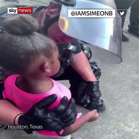 Protesters watch as police in riot gear walk down a residential street in st. George Floyd death: Policeman hugs crying black girl who asked 'are you gonna shoot us?' during ...